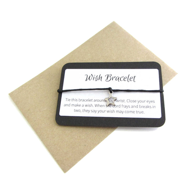 stainless steel hollow star charm on black cord string attached to a message card stating 'sarah' and note to make a wish when tying the bracelet around a wrist with a brown craft paper envelope