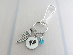 stainless steel single angel wing charm, a laser engraved baby footprints charm and a blue/green coloured crystal charm on a bag charm with snap clip hook