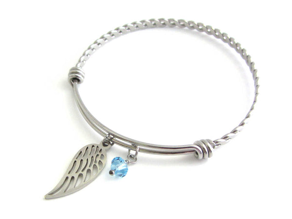 stainless steel single angel wing charm and a light blue crystal charm on a bangle with braided twist pattern