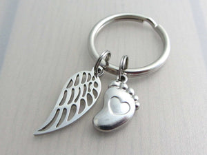 stainless steel single angel wing charm and a single foot charm with indented heart on a keyring