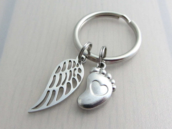 stainless steel single angel wing charm and a single foot charm with indented heart on a keyring