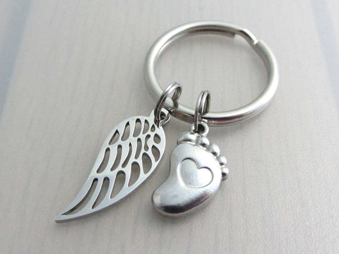 stainless steel single angel wing charm and a single foot charm with indented heart on a keyring