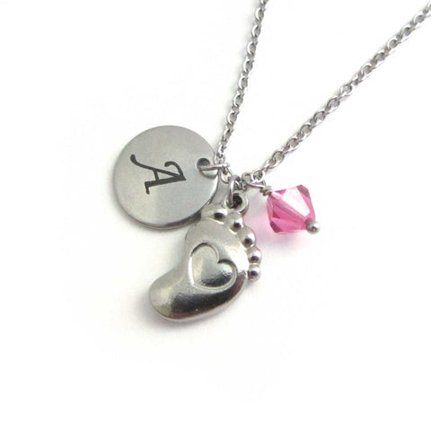 laser engraved capital initial letter disc charm, a single baby foot with indented heart charm and a pink crystal charm on a stainless steel chain