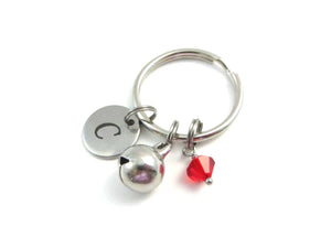laser engraved capital initial letter disc charm, stainless steel bell charm and a red crystal charm on a keyring