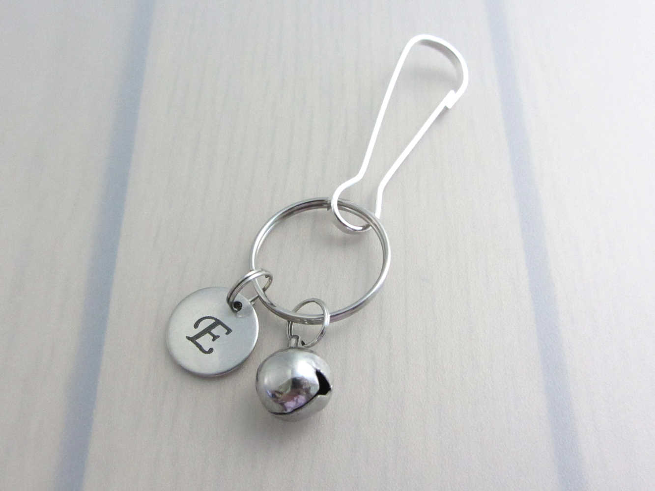 stainless steel laser engraved capital initial letter disc charm and bell charm on a bag charm with snap clip hook