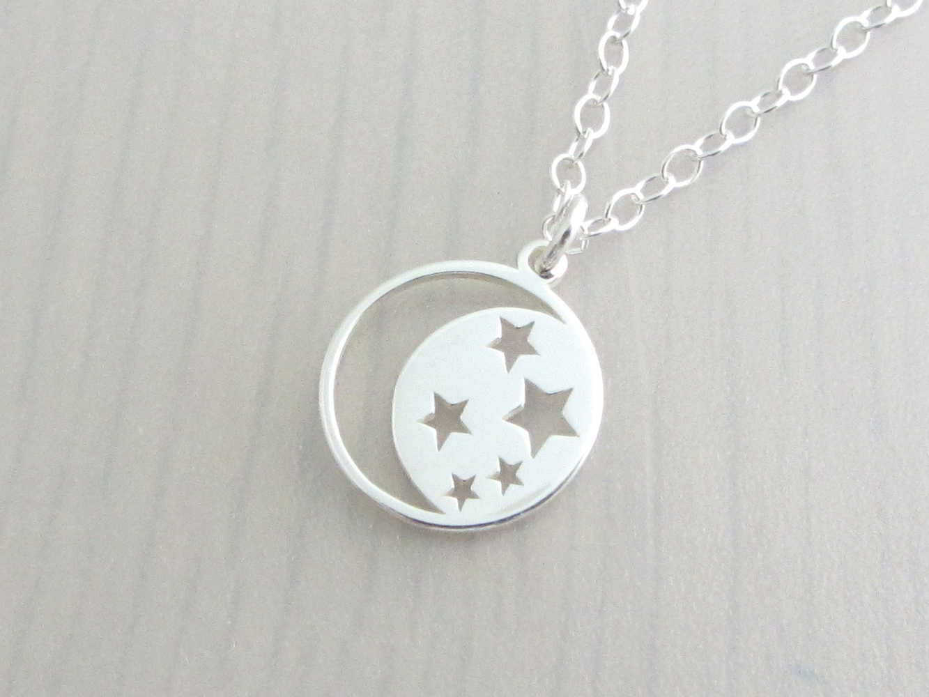 silver crescent moon with cut out stars charm on a silver chain