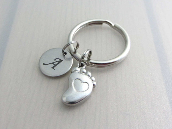 stainless steel laser engraved capital initial letter disc charm and a single foot charm with indented heart on a keyring