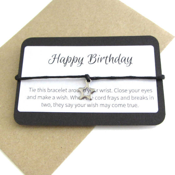 stainless steel hollow star charm on black cord string attached to a message card stating 'happy birthday' and note to make a wish when tying the bracelet around a wrist with a brown craft paper envelope