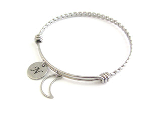 stainless steel laser engraved capital initial letter disc charm and hollow crescent moon charm on a bangle with braided twist pattern