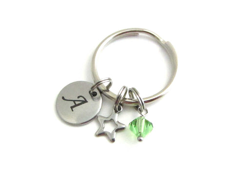 stainless steel laser engraved capital initial letter disc charm, hollow star charm and a light green crystal charm on a keyring