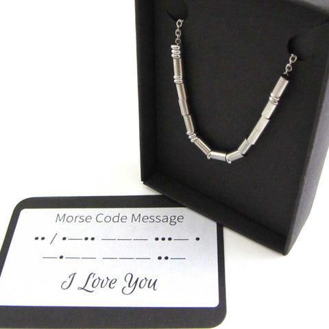 close up of 'i love you' necklace written in morse code stainless steel beads on a stainless steel chain shown in box with i love you morse code message card
