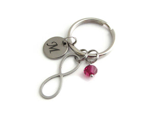 laser engraved capital initial letter disc charm, stainless steel infinity charm and a red crystal charm on a keyring