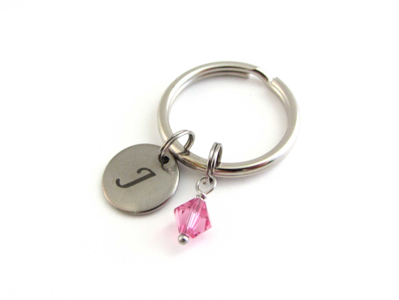 stainless steel laser engraved capital initial letter disc charm and a pink crystal charm on a keyring