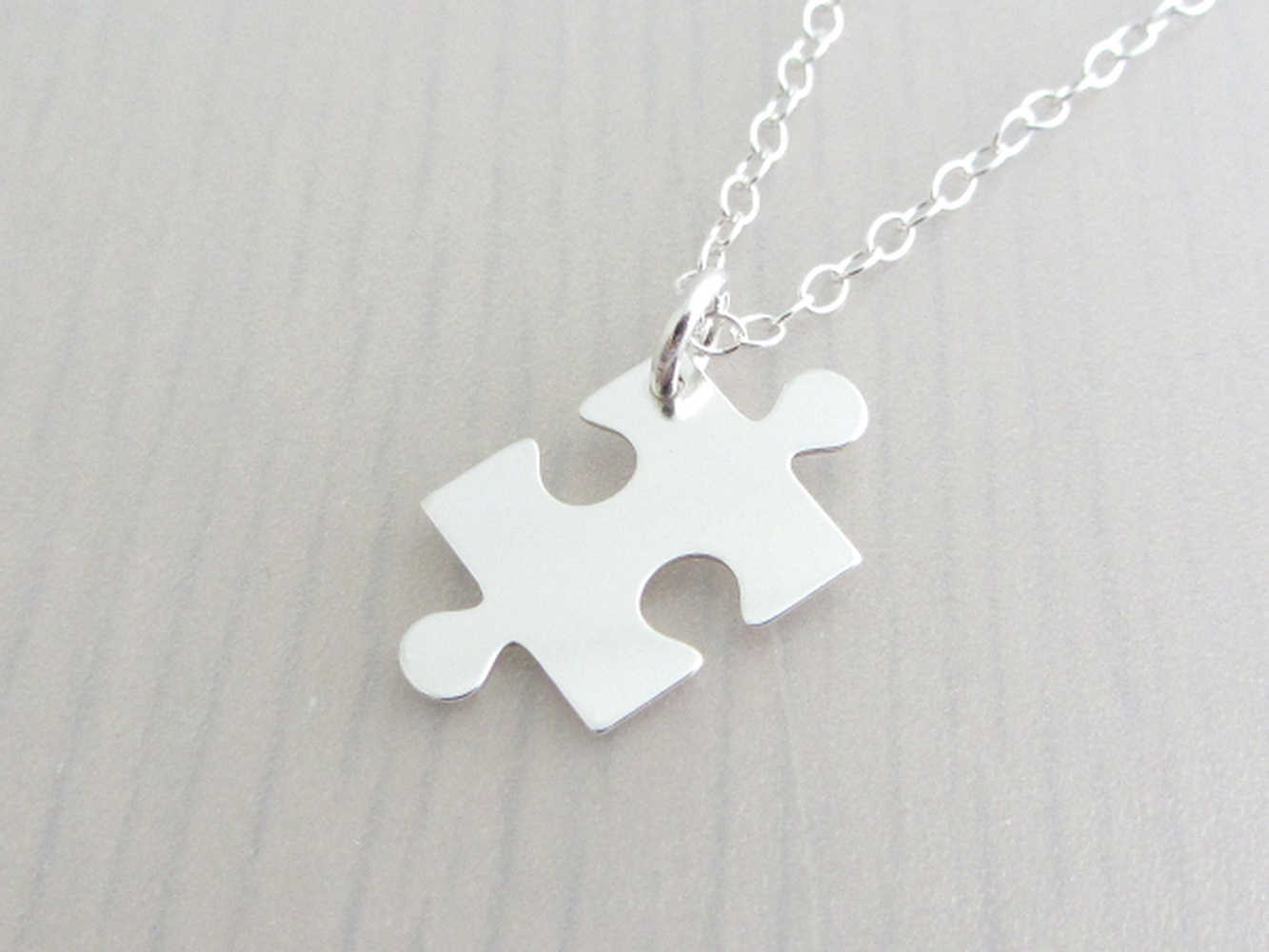 silver jigsaw puzzle piece charm on a silver chain