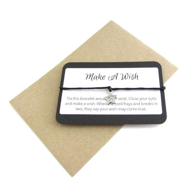 stainless steel hollow star charm on black cord string attached to a message card stating 'make a wish' and note to make a wish when tying the bracelet around a wrist with a brown craft paper envelope
