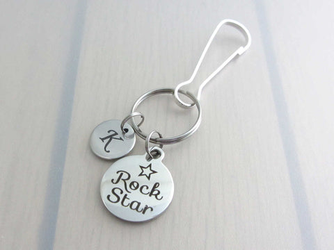 stainless steel laser engraved capital initial letter disc charm and laser engraved "rock star" with star charm on a bag charm with snap clip hook