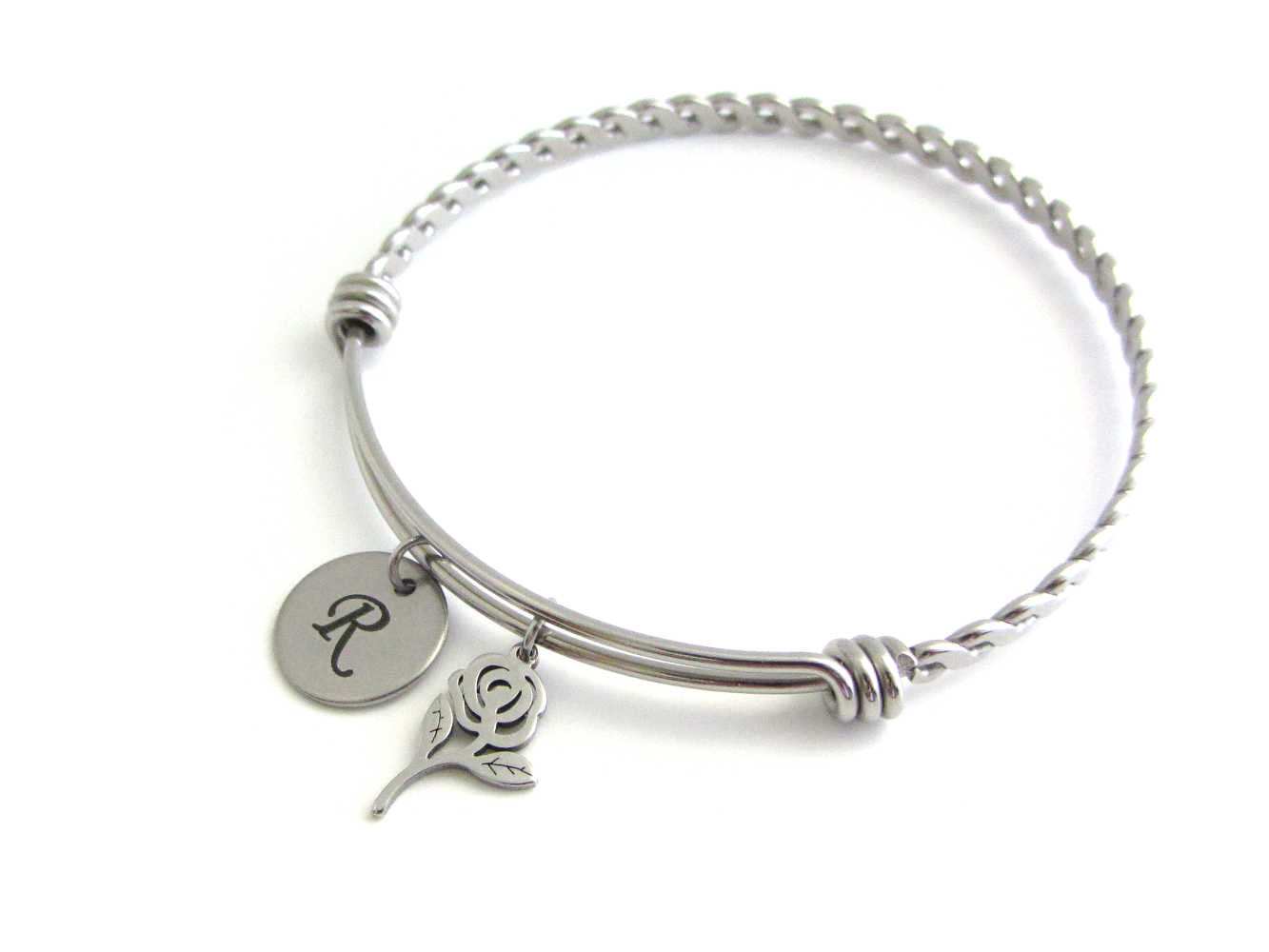 laser engraved capital initial letter disc charm and a rose flower charm on a bangle with braided twist pattern