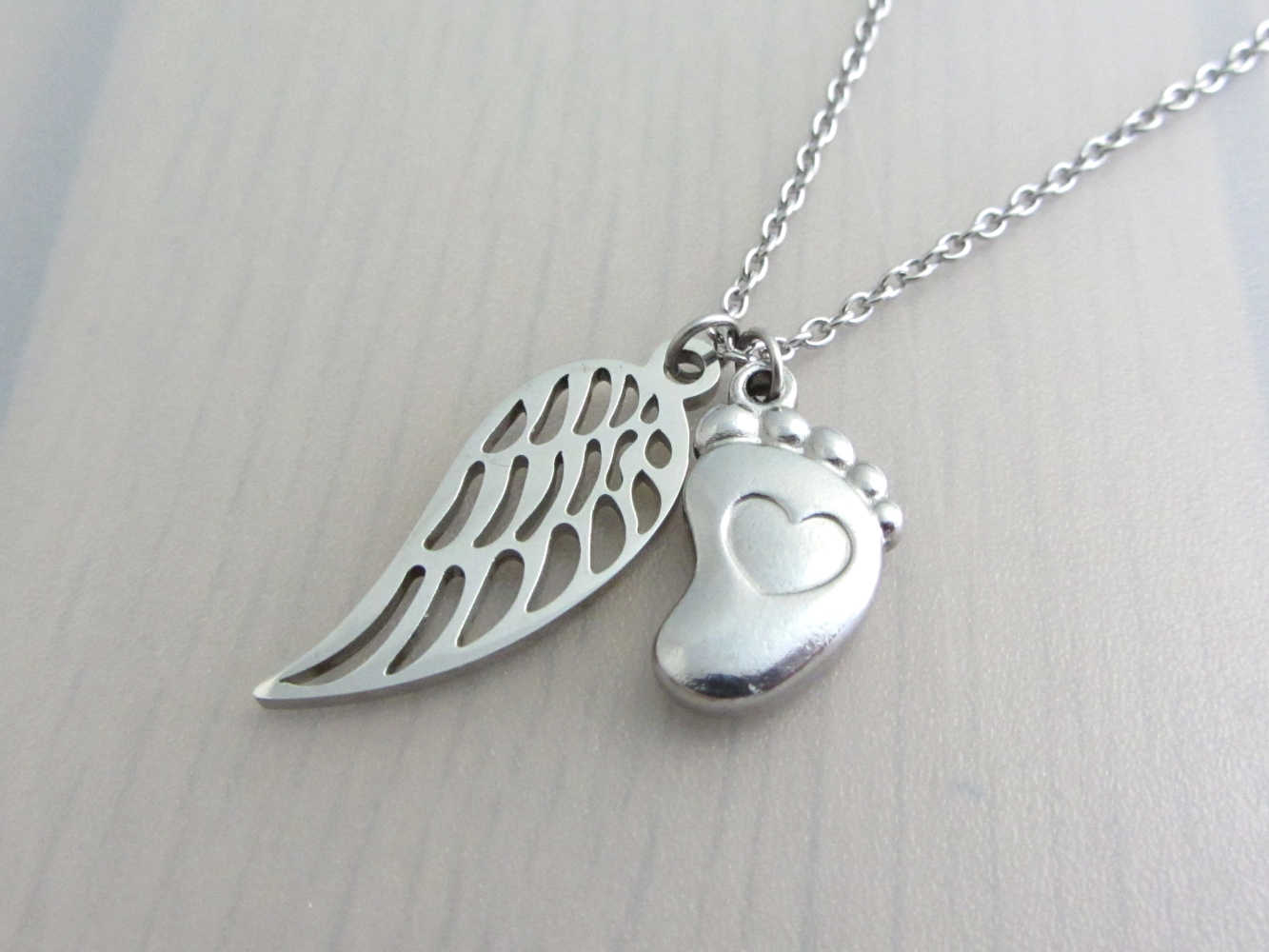 single angel wing charm and a single foot charm with indented heart on a stainless steel chain