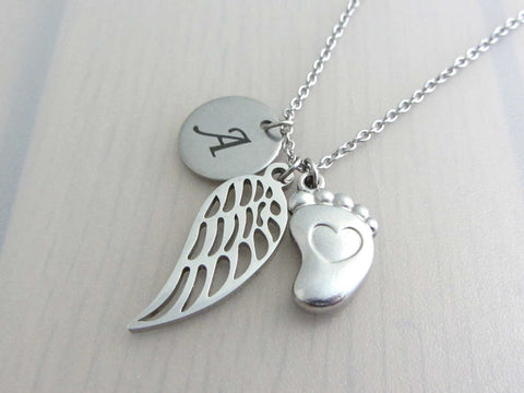 laser engraved capital initial letter disc charm, a single angel wing charm and a single foot charm with indented heart on a stainless steel chain