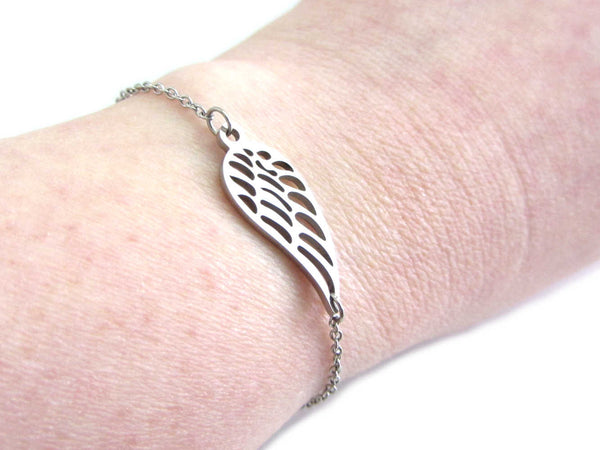 single angel wing charm on a stainless steel chain bracelet on wrist