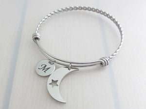 stainless steel laser engraved capital initial letter disc charm and crescent moon with cut out star charm on a bangle with braided twist pattern