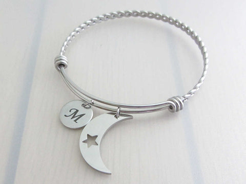 stainless steel laser engraved capital initial letter disc charm and crescent moon with cut out star charm on a bangle with braided twist pattern