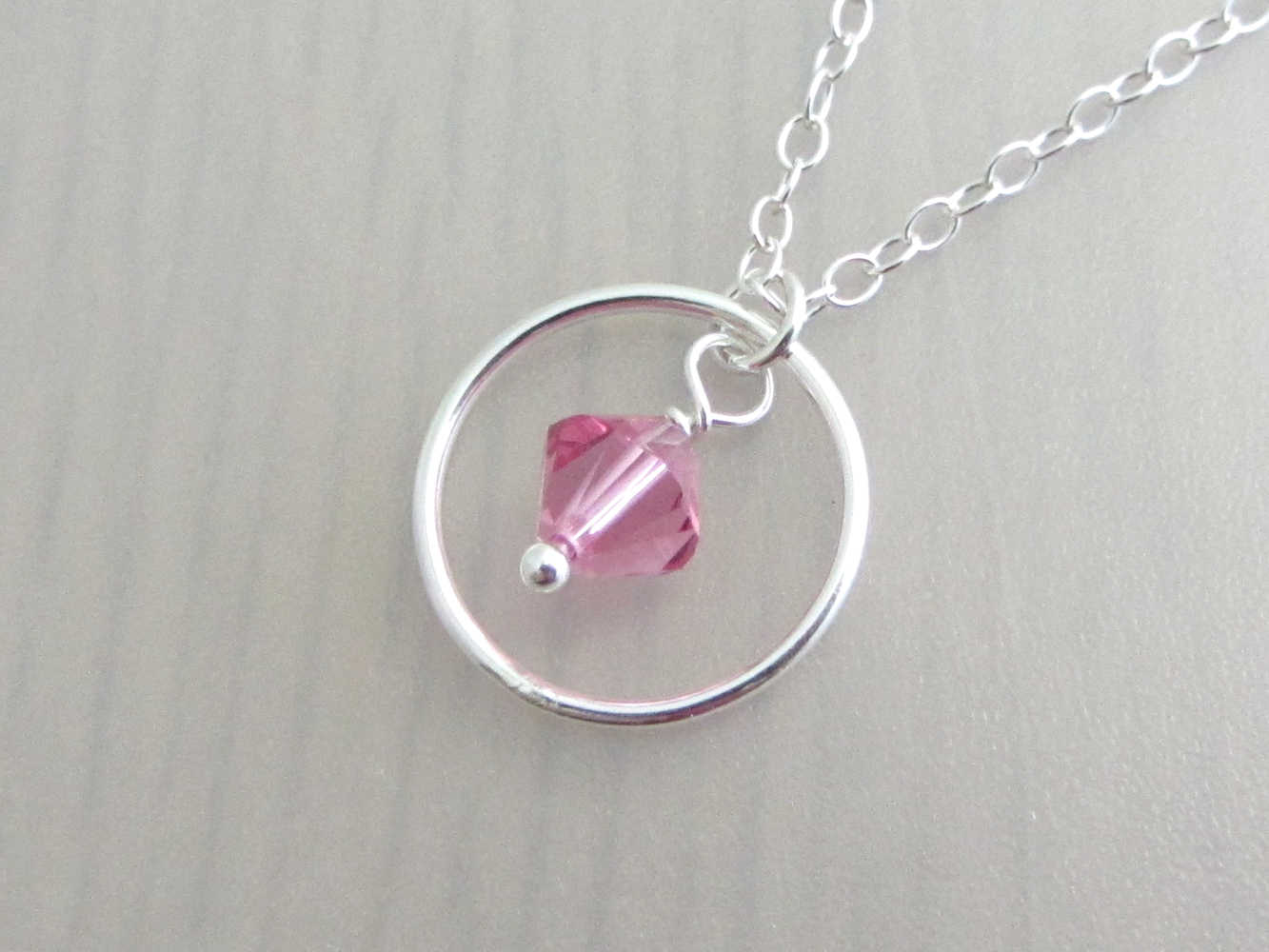 silver circle ring and pink coloured crystal charm on a silver chain