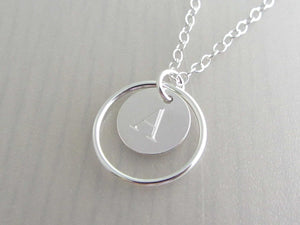 silver circle ring and engraved capital initial letter disc charm on a silver chain