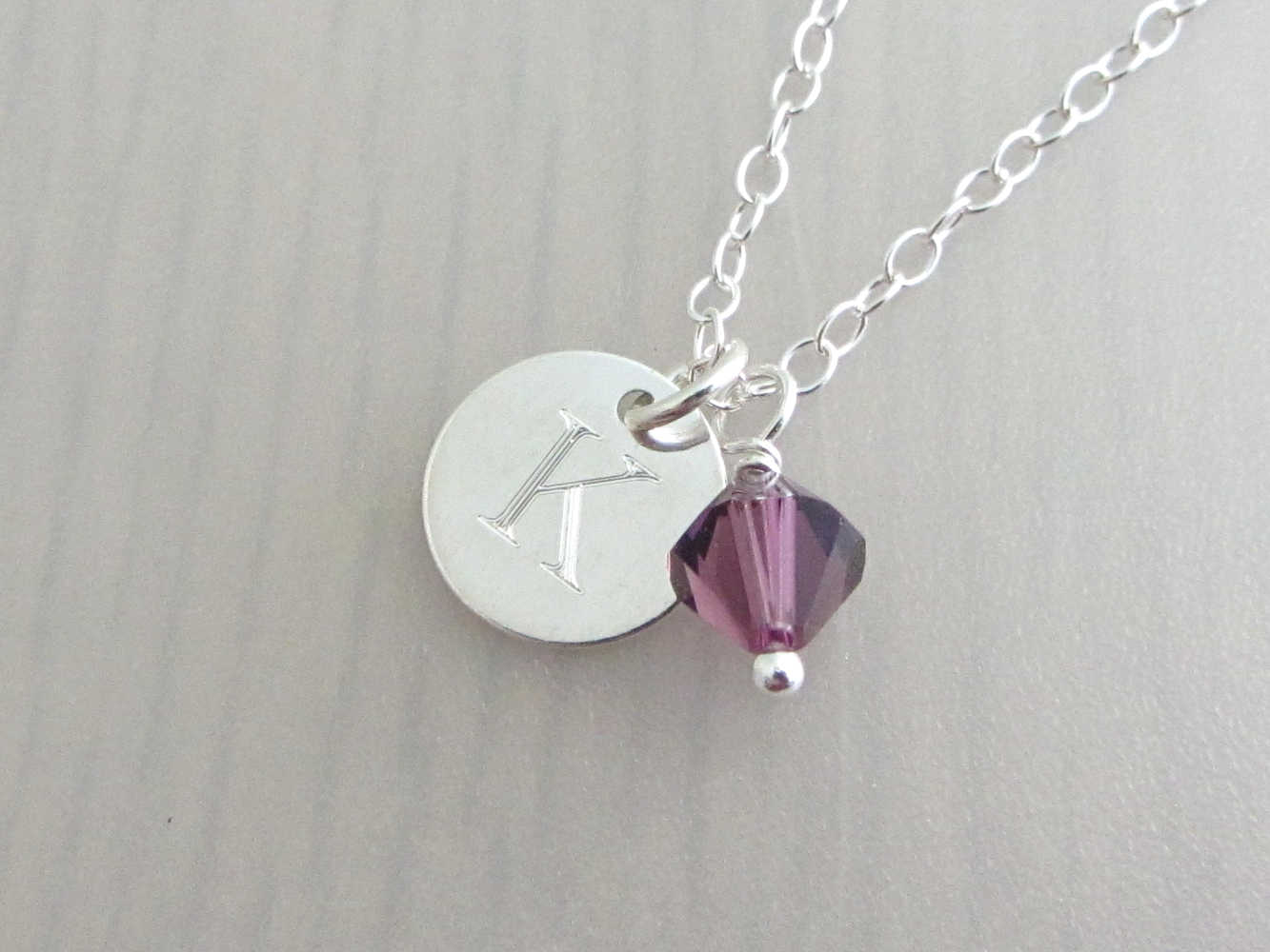 silver engraved capital initial letter disc charm and purple coloured crystal charm on a silver chain