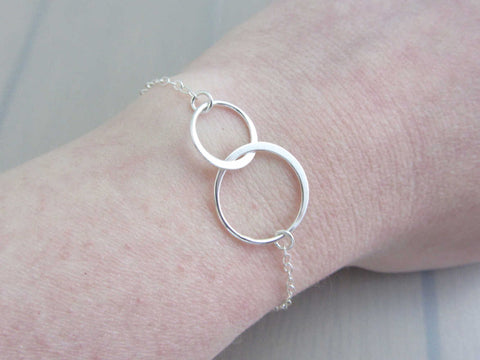 two linked silver circle rings on a silver chain bracelet on wrist