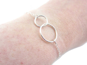 two linked silver circle rings on a silver chain bracelet on wrist