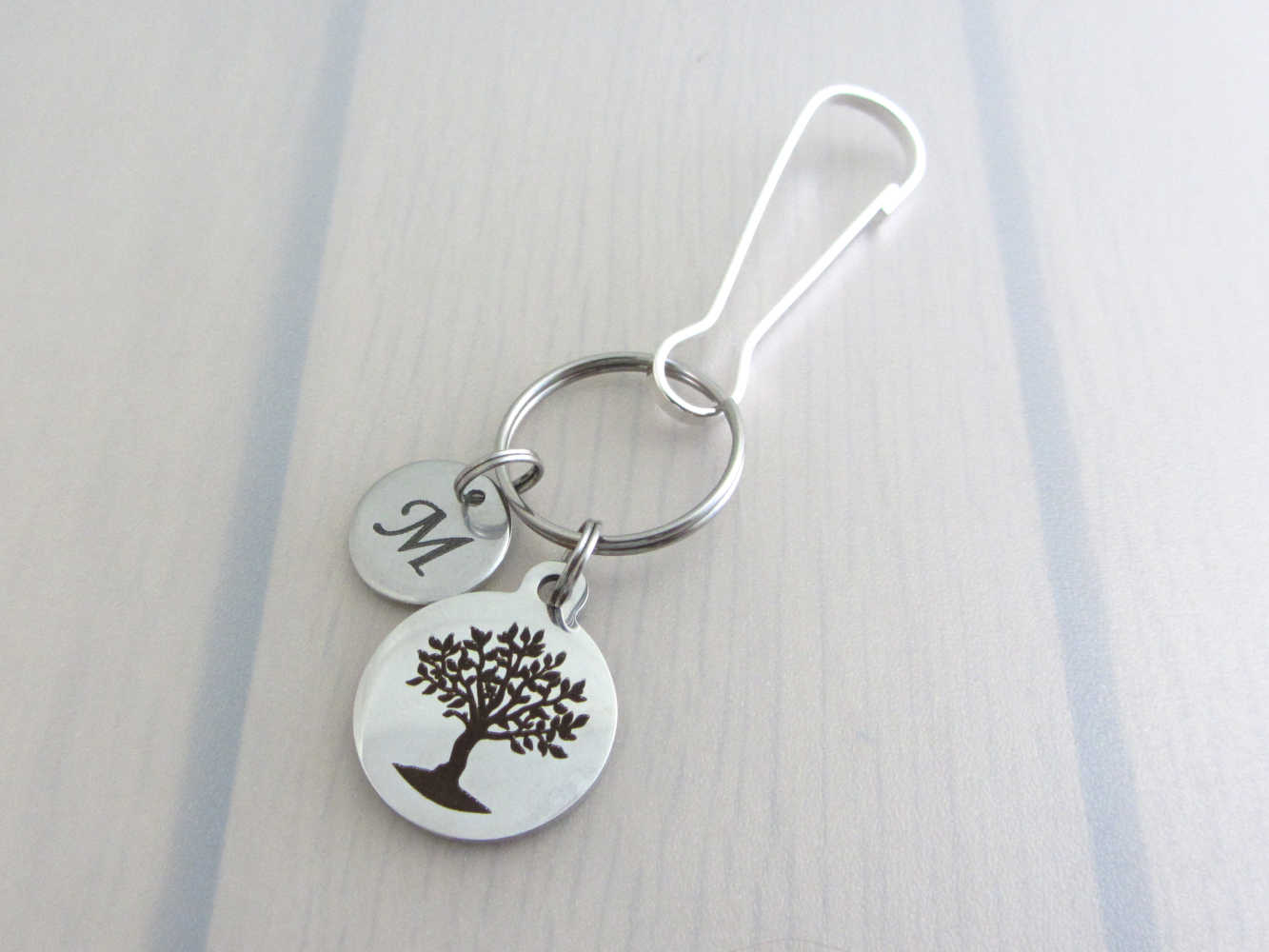 laser engraved capital initial letter disc charm and a laser engraved tree charm on a bag charm