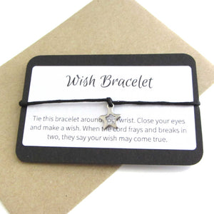 stainless steel hollow star charm on black cord string attached to a message card stating 'wish bracelet' and note to make a wish when tying the bracelet around a wrist with a brown craft paper envelope