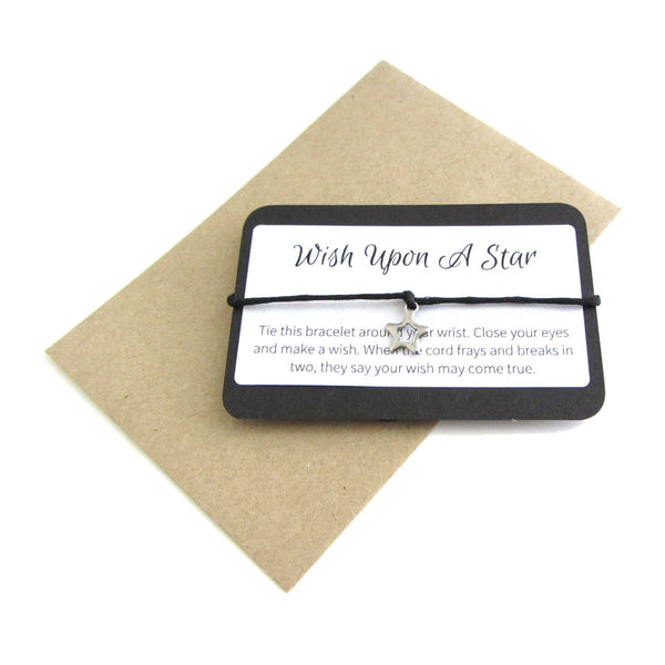 stainless steel hollow star charm on black cord string attached to a message card stating 'wish upon a star' and note to make a wish when tying the bracelet around a wrist with a brown craft paper envelope