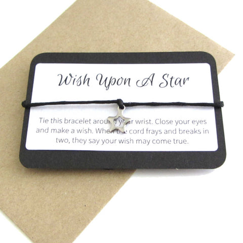 stainless steel hollow star charm on black cord string attached to a message card stating 'wish upon a star' and note to make a wish when tying the bracelet around a wrist with a brown craft paper envelope